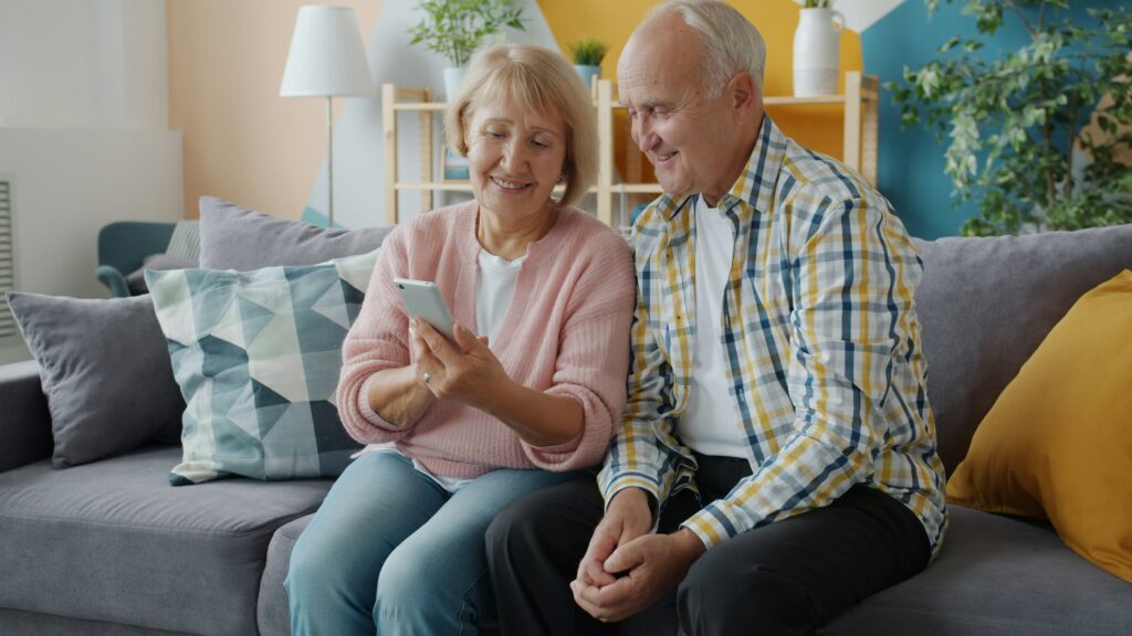older couple sitting on the couch looking at a smartphone